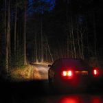 883525 – car with lights on the road in deep forest at the night.